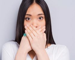 dark haired woman covering mouth with both hands