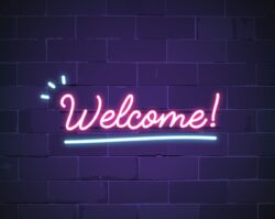 Neon pink WELCOME sign with blue accents against a purple brick wall in Overland Park, KS