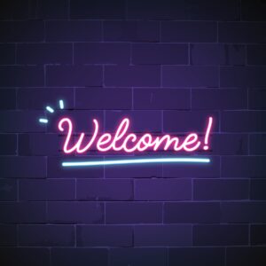 Neon pink WELCOME sign with blue accents against a purple brick wall in Overland Park, KS