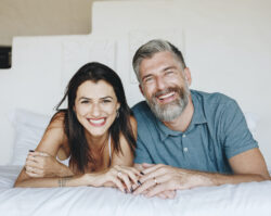 A brunette woman smiles next to her husband with salt and pepper hair and blue polo