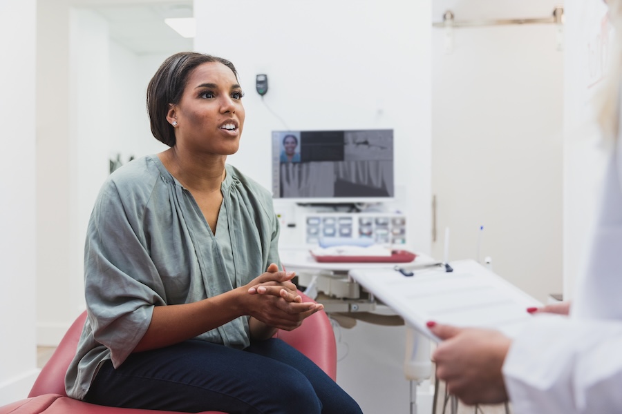 woman talking about warning signs in the mouth with dentist